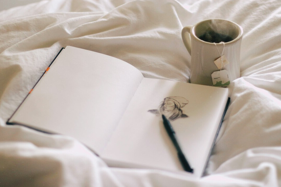 Hand writing in a notebook on a desk